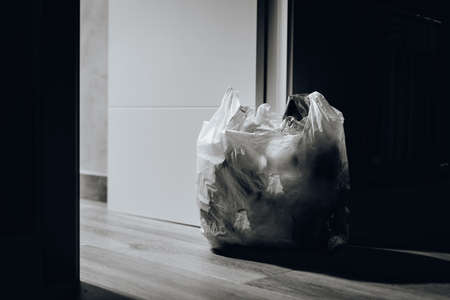A black and white shot of a trash bag near doorの写真素材