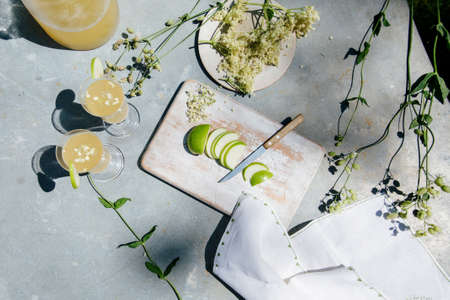A high angle shot of slices of apple and two glasses of lemonade and flowers on a wooden surfaceの写真素材