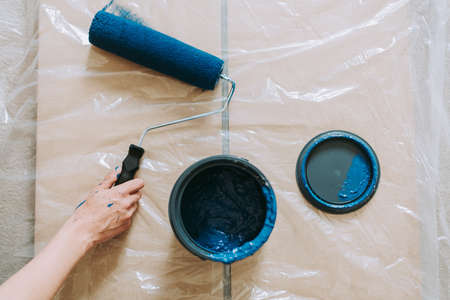 A closeup shot of a female using paint rollers with the color blue