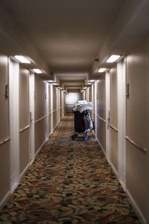 A hotel hallway with a cart of fresh white towelsの写真素材