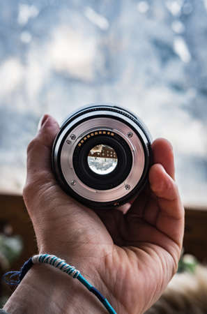 A hand with a bracelet holding a large camera lensの写真素材