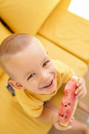 A Caucasian young boy eating watermelon and smilingの写真素材