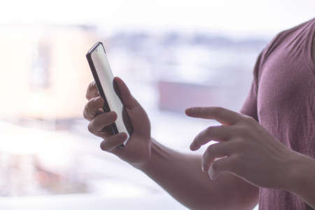 A person wearing a pink shirt using a smartphone at daytime