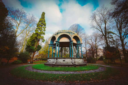 A beautiful gazebo in the middle of the park with trees and grassy fieldの写真素材