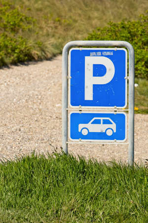 A vertical closeup shot of a parking sign near green grass by the roadの写真素材