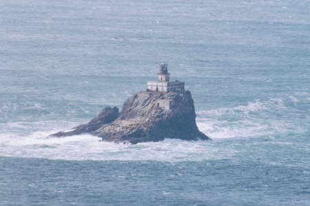 A lighthouse built on a rock during the day in the beautiful sea