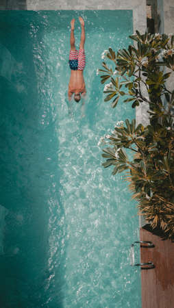 A vertical shot of a male in american flag swimsuit swimming in a pool