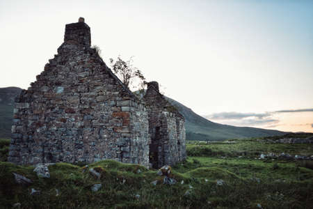 Destroyed and abandoned stone house in a fieldの写真素材