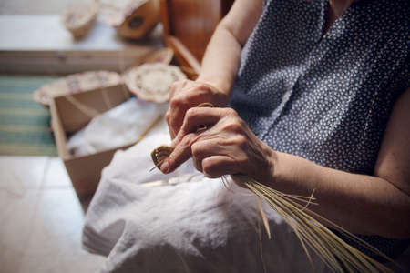 A shallow focus closeup shot of an elderly female's hands weaving a basket in Castelsardo, Sardinia, Italyの写真素材
