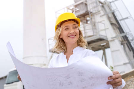 A low angle shot of a young caucasian female engineer wearing a hard hat on a construction site