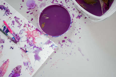 An overhead shot of purple paint in a bowl with purple spots and marks on paperの写真素材