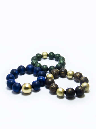 A closeup shot of three bracelets with blue, golden and brown gem stones
