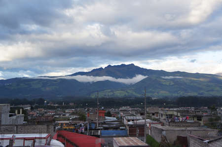A town with houses with a mountain covered with fog on the backgroundの写真素材