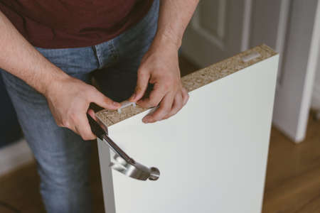 A person hammering a drawer in a house
