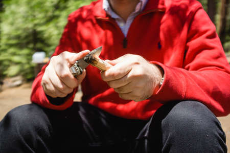 A male in a red jacket sharpening his knife in the wildの写真素材