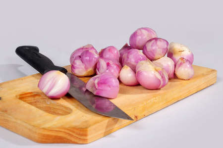 An isolated view of peeled shallots on the wooden cutting board on an empty backgroundの写真素材