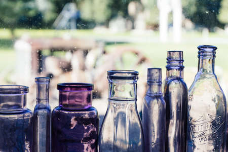 Different sized and shaped empty glass bottles in a row with a blurred background