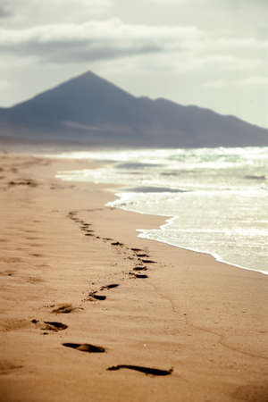 The footprints on a sandy beach with a mountain in background in the Canary Islands, Spain