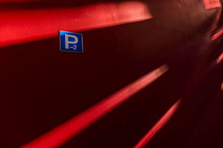 A red wall with shadows on it in the basement floor if a parking garage