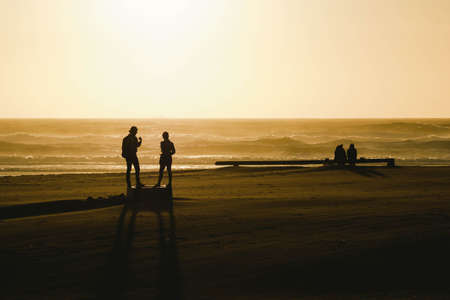 Silhouettes of people on the beach during beautiful sunsetの写真素材