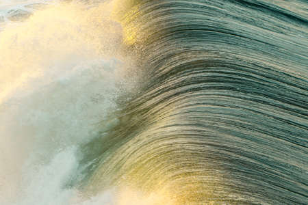 A closeup of beautiful sea waves splashing during a sunny day at the beachの写真素材