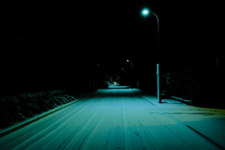 A dimly lit road at night with a street lamp