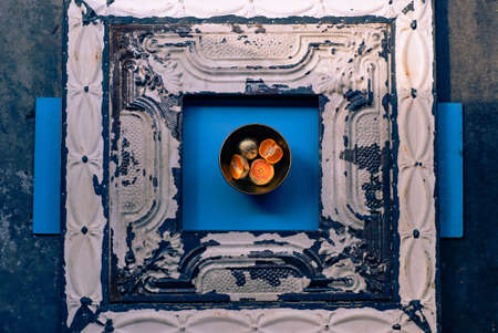 An abstract photography of metal plated mandarins in a bowl on a blue and wooden surface