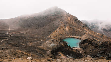 A beautiful aerial shot of a small lake in the middle of the desert near a mountain on a foggy dayの写真素材