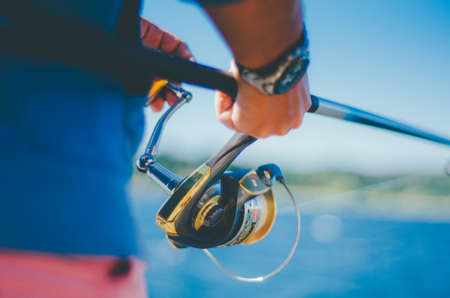 A closeup of a male's hand using a fishing rod