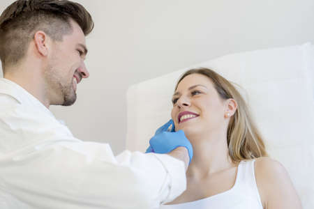 A closeup of a doctor performing cosmetic surgery on a young female under the lights
