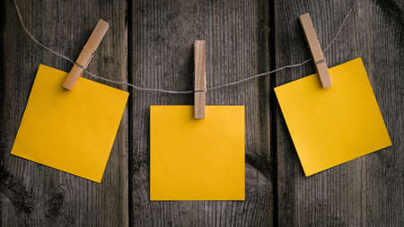 A closeup shot of a hanging yellow paper on a wooden clip