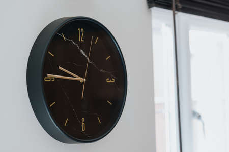 A closeup shot of a black clock on a white wall inside a modern house