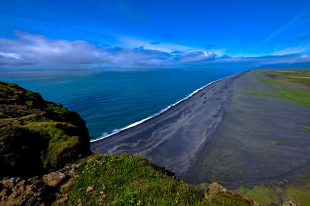 An aerial shot of shoreline near the mountain under a blue sky at daytime
