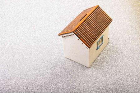 A 3D illustration of a white house with brown roof on a grey surface - perfect for backgroundの写真素材