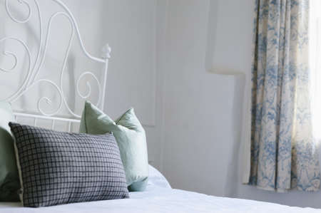 A shot of a white bed with blue and light blue pillowsの写真素材