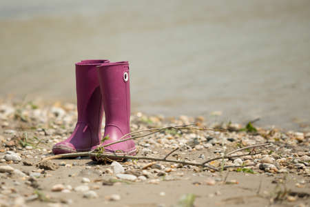 A closeup shot of two purple boots next to each other on the ground behind the waterの写真素材