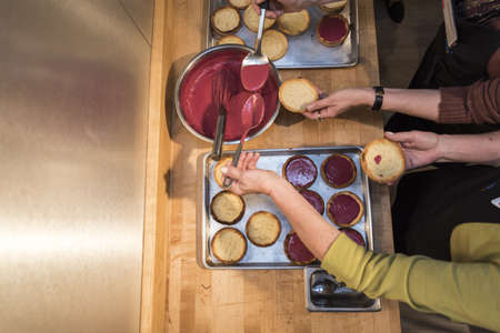 An overhead shot of two females putting jam on pancakes