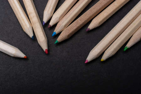 A closeup shot of a set of wooden color pencils on a black surface  - an art conceptの写真素材