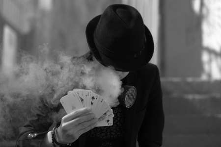 A grayscale portrait of a mystical male gamer's hand holding poker cards with smoke in the foregroundの写真素材