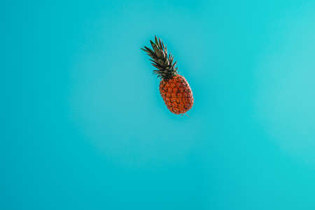 Golden pineapple flying through a teal-blue sky.の写真素材
