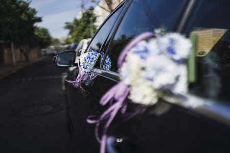 A close up shot of wedding flowers in white and blue attached to car windowsの写真素材