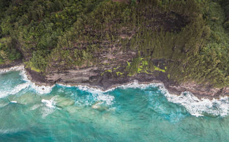 A beautiful aerial shot of the coast of Napali with clear beautiful water and steep rocks during a...
