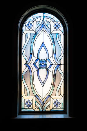 A vertical shot of a beautiful decorative window in a dark churchの写真素材