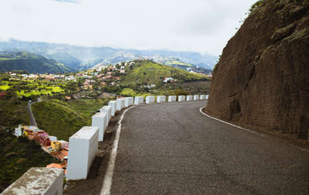 Road next a hill with white roadside pillars in a large valley