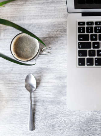 An overhead shot of a laptop with a coffee and a spoon on a wooden tableの写真素材