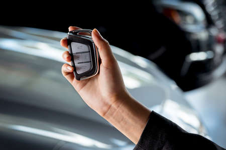 A woman's hand holding a remote key of a new SUV car