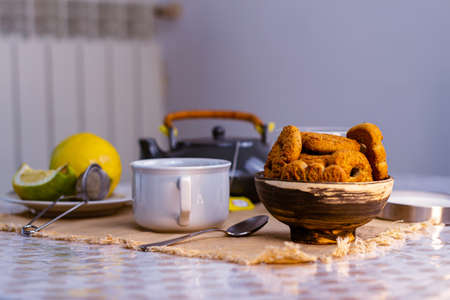 A closeup shot of a dessert table with tea cup and lemon and cookies in a bowlの写真素材