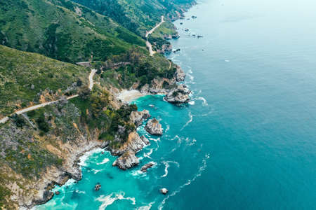 An aerial shot of the beautiful shoreline of the sea with rocks and greenery on the beachの写真素材