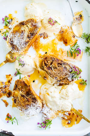 Apple Strudel with Passionfruit Curd and Ice Cream and edible flowers as garnishの写真素材