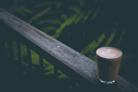 A well made latte with art on foam on a wooden fenceの写真素材